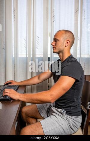 Allievo giovane maschio allegro che gode del webinar di formazione sul computer portatile che prepara il programma di coursework, libero professionista felice Sfoglia il video su netbook cr Foto Stock