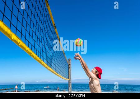 Il ragazzo sportivo gioca a Beach volley a Ost See in una giornata di sole Foto Stock