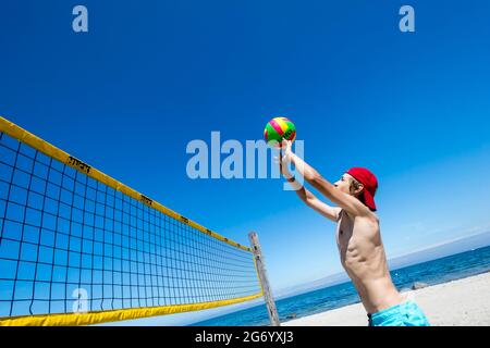 Il ragazzo sportivo gioca a Beach volley a Ost See in una giornata di sole Foto Stock