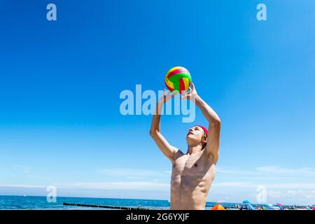 Il ragazzo sportivo gioca a Beach volley a Ost See in una giornata di sole Foto Stock