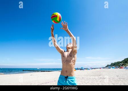 Il ragazzo sportivo gioca a Beach volley a Ost See in una giornata di sole Foto Stock