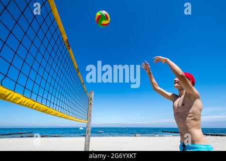 Il ragazzo sportivo gioca a Beach volley a Ost See in una giornata di sole Foto Stock