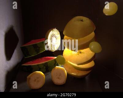 Concetto creativo di frutta volante affettata in una scatola nera con un lampo di luce Foto Stock