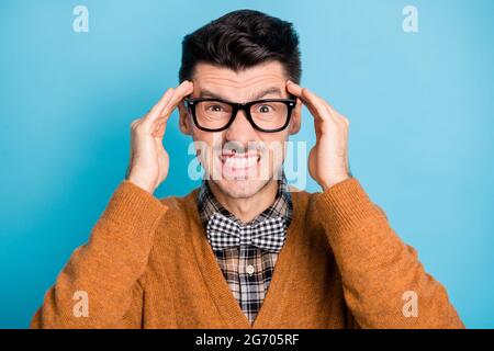 Foto di arrabbiato ragazzo infastidito tenere dita testa mani indossare occhiali isolati su sfondo blu Foto Stock