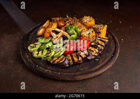 banner. una grande porzione di verdure fritte colorate e funghi su un vassoio di legno su uno sfondo scuro. Foto Stock