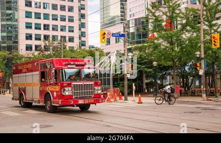 TORONTO, CANADA - 06 05 2021: Red Toronto Fire Services Squad Heavy Rescue Truck che gira da King a John Street di fronte alla Metro Hall 27 piani Foto Stock