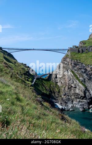 Il nuovo ponte pedonale del Castello di Tintagel per l'Isola del Castello di Tintagel con le rovine, la Grotta di Merlins e Tintagel Haven Cove. Dal South West Coast Path. Foto Stock