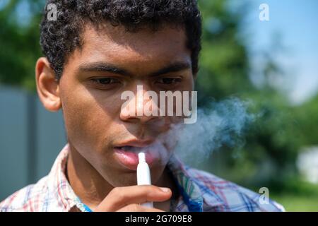 Primo piano giovane brasiliano che vaping e-sigaretta con e-Liquid Foto Stock