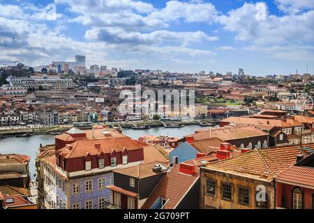 Ampia vista sulla città di Porto, Portogallo con il fiume Douro e caratteristici tetti in terracotta. Giornata di sole con cielo blu e nuvole soffici. Foto Stock