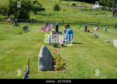 Un uomo paga i suoi rispetti ad un marcatore grave in un cimitero il giorno del Memorial Day negli Stati Uniti. Foto Stock