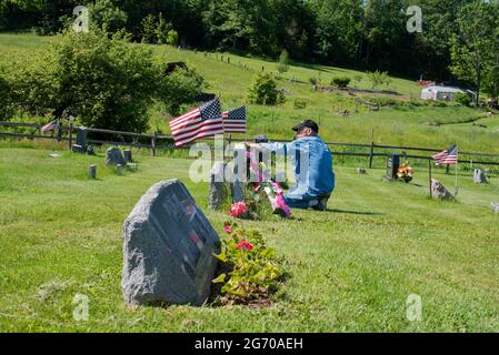 Un uomo paga i suoi rispetti ad un marcatore grave in un cimitero il giorno del Memorial Day negli Stati Uniti. Foto Stock