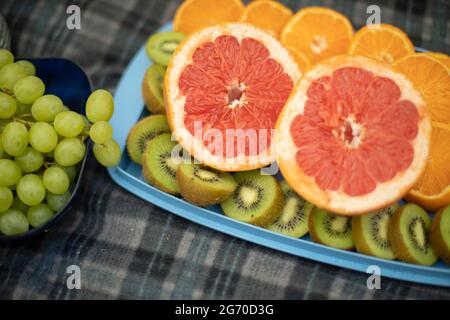 Frutta in un picnic. Mango e kiwi. Cibo sano in natura. Frutta fresca. Vitamine in estate. Affettato kiwi e mango su un piatto. Foto Stock