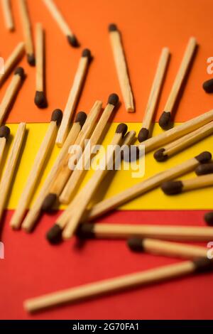 Alcuni fiammiferi di legno su una superficie di colore giallo, rosso e arancione Foto Stock