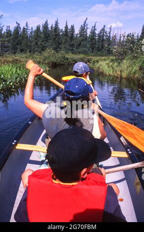 Vacanza in famiglia: Madre e due bambini in canoa sul fiume dal lago Kawawaymog verso il lago North Tea, Algonquin, Ontario, Canada. Foto Stock