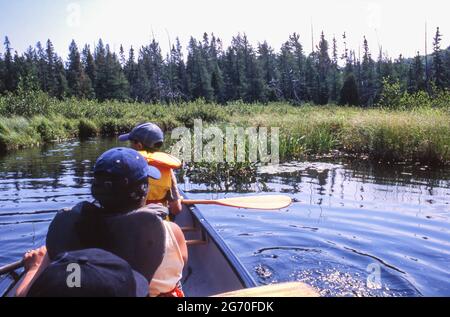 Vacanza in famiglia: Madre e due bambini in canoa sul fiume dal lago Kawawaymog verso il lago North Tea, Algonquin, Ontario, Canada. Foto Stock