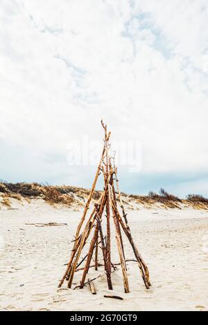 Una struttura di ricovero fatta di rami di legno su una spiaggia di sabbia Foto Stock