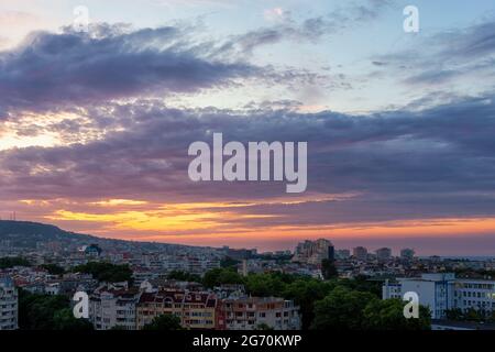 Arancio alba cielo con viola blu pittoresche nuvole sulla città addormentata. Cielo di alba color pastello su Varna. L'alba calma si alza nel cielo. Foto Stock
