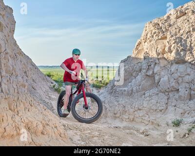 L'uomo anziano sta cavalcando una mountain bike grassa in badlands di Pawnee National Grassland nel nord del Colorado Foto Stock