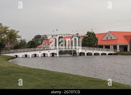 Olanda, MI, USA - 8 giugno 2008: Nelis Dutch Village. Paesaggio con tipico ponte storico pull-up sopra l'acqua di stagno sotto il cielo grigio. Tetto rosso mod Foto Stock