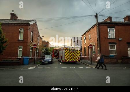 Manchester, Regno Unito. 09 luglio 2021. Coppia passeggiate oltre la cassetta di polizia presso la scena del fuoco a ManchesterGreater Manchester Fire Service blocco fuori Norman Street, Failsworth dopo un incendio casa in un appartamento su Manchester Road. I residenti dicono che il fuoco della casa è stato causato da un uomo che ha voluto commettere suicidio, tuttavia rapporti contrastanti anche mi è venuto che l'uomo stava cucinando. Due camion dei vigili del fuoco e un comandante dei vigili del fuoco hanno risposto alla scena. (Foto di Ryan Jenkinson/SOPA Images/Sipa USA) Credit: Sipa USA/Alamy Live News Foto Stock