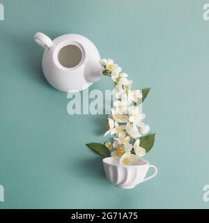 Layout di teiera e tazza da tè con fiori di gelsomino su sfondo verde. Tè Jasmine. Foto Stock