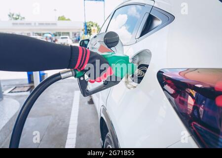 Impianto di rifornimento del veicolo presso il distributore di benzina. Auto bianca al distributore di benzina in fase di rifornimento di carburante. Rifornimento manuale dell'auto con carburante presso la stazione di rifornimento. T Foto Stock