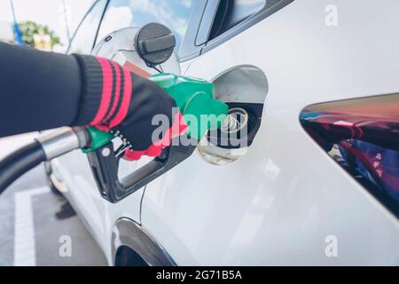 Impianto di rifornimento del veicolo presso il distributore di benzina. Auto bianca al distributore di benzina in fase di rifornimento di carburante. Rifornimento manuale dell'auto con carburante presso la stazione di rifornimento. T Foto Stock