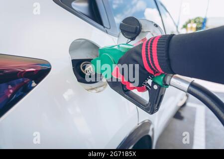 Impianto di rifornimento del veicolo presso il distributore di benzina. Auto bianca al distributore di benzina in fase di rifornimento di carburante. Rifornimento manuale dell'auto con carburante presso la stazione di rifornimento. T Foto Stock