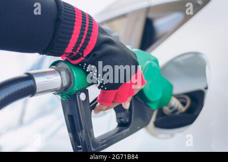 Impianto di rifornimento del veicolo presso il distributore di benzina. Auto bianca al distributore di benzina in fase di rifornimento di carburante. Rifornimento manuale dell'auto con carburante presso la stazione di rifornimento. T Foto Stock