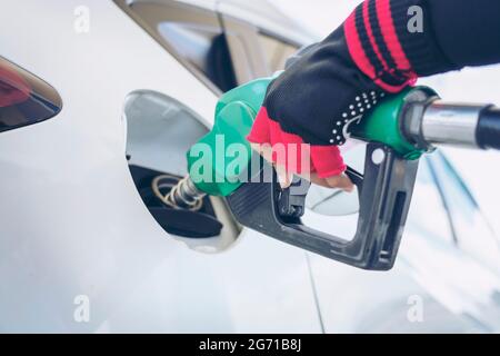 Impianto di rifornimento del veicolo presso il distributore di benzina. Auto bianca al distributore di benzina in fase di rifornimento di carburante. Rifornimento manuale dell'auto con carburante presso la stazione di rifornimento. T Foto Stock