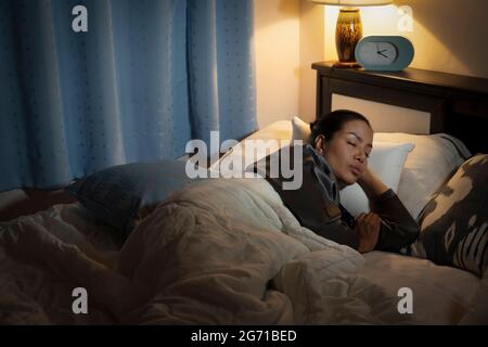 Bellezza donna ispanica in accappatoio a casa camera da letto sdraiata sul letto a tarda notte cercando di dormire soffrendo insonnia disturbi del sonno o spaventato su incubi Foto Stock