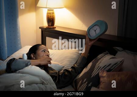 Bellezza donna ispanica in accappatoio a casa camera da letto sdraiata sul letto a tarda notte cercando di dormire soffrendo insonnia disturbi del sonno o spaventato su incubi Foto Stock