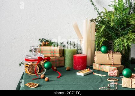 Tavolo festoso decorato Natale o Capodanno, rami thuja e abete rosso, palle di Natale e fette di agrumi secchi, candele e confezioni regalo Foto Stock