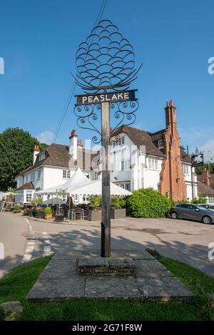 Peaslake, grazioso villaggio nel Surrey Hills AONB, Inghilterra, Regno Unito. Cartello Village e l'Hurtwood Inn. Foto Stock