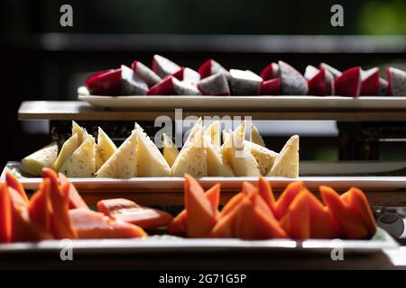 frutta tropicale a fette come ananas, dragonfruit e papaya matura pronta da mangiare e servita sul vassoio bianco del ristorante per pranzo al sole Foto Stock