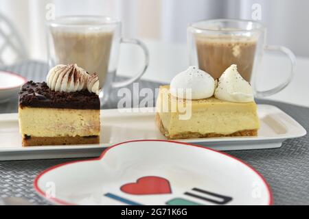 Messa a fuoco selettiva di due pezzi di torta e di tazze di caffè in un bar Foto Stock