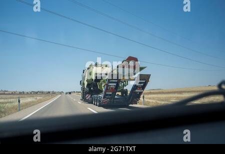 Guida dietro un autocarro pesante che trasporta una mietitrice. Trasporti pesanti. Vista dall'interno della vettura Foto Stock