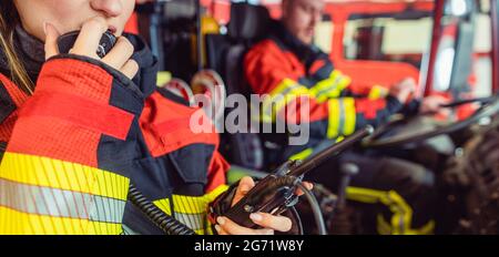 Fuoco donna combattente in servizio utilizzando la radio in camion antincendio Foto Stock