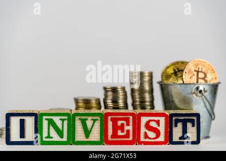 Monete di soldi impilano scalino come crescita crescente di punto e blocco di cubo di legno con l'INVESTIMENTO di parola. Concetto di investimento e risparmio di denaro. Investire su bitcoin. Investite su Foto Stock