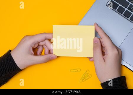 Donna mano tenere vuoto Note scrivere nuovo Messege aggiornamenti idee accanto al portatile. Lady Palm mostra inviluppo piegatura lettere di invio Indirizzo postale e. Foto Stock