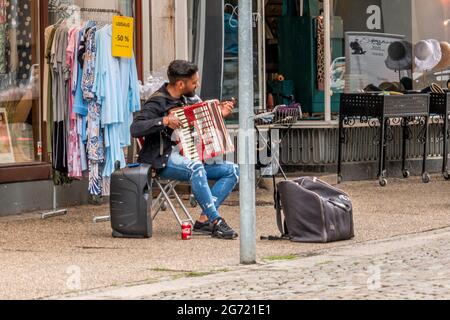 Randers, Danimarca - 10 luglio 2021: Musicista di strada seduto e suonando per strada Foto Stock