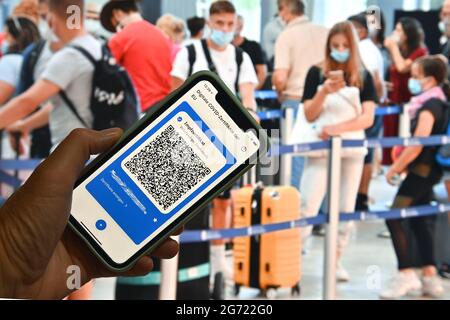 Foto dell'argomento/simbolo: Certificati COVID digitali dell'UE su smartphone, protezione completa della vaccinazione, certificato di vaccinazione, pass di vaccinazione digitale, scheda di vaccinazione. I viaggiatori d'aria, come qui all'aeroporto Albrecht Duerer di Norimberga stand con maschera facciale, maschera di fronte al check-in, banco, check-in. Viaggiatori con i loro bagagli in vacanza. Foto Stock