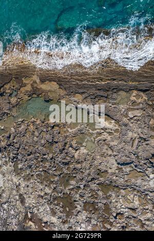Piscine di marea durante la bassa marea. Spiaggia rocciosa con texture spettacolare, vista dall'alto verticale Foto Stock