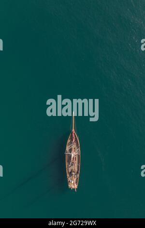 Vista aerea dall'alto di una bella nave a vela ad albero alto che galleggia su un tranquillo oceano turchese con spazio per le copie Foto Stock