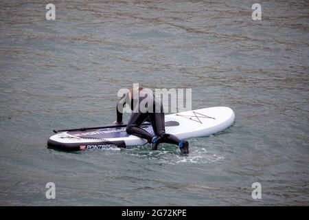 Porthleven, Cornovaglia, 10 luglio 2021, UNA giovane signora che si gode paddle boarding nel porto di Porthleven, Cornovaglia . La temperatura è stata di 18C, la previsione è per le docce tuose domani.Credit: Keith Larby/Alamy Live News Foto Stock