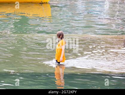 Porthleven, Cornovaglia, 10 luglio 2021, UNA giovane ragazza cammina completamente vestita nel mare a Porthleven, Cornovaglia . La temperatura è stata di 18C, la previsione è per le docce tuose domani.Credit: Keith Larby/Alamy Live News Foto Stock