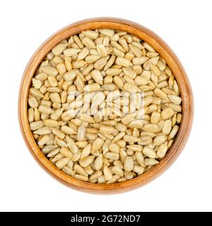 Semi di girasole sbucciati, arrostiti e salati, in una ciotola di legno. Noccioli croccanti, frutti del girasole comune, Helianthus Annuus, pronti a mangiare. Foto Stock