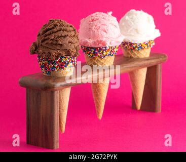 Coni di gelato alla fragola e alla vaniglia al cioccolato con Sprinkles su uno sfondo rosa brillante Foto Stock