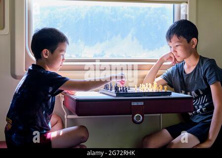 Ragazzi che giocano a scacchi vicino alla finestra in treno viaggio, concetto di giochi da tavolo Foto Stock