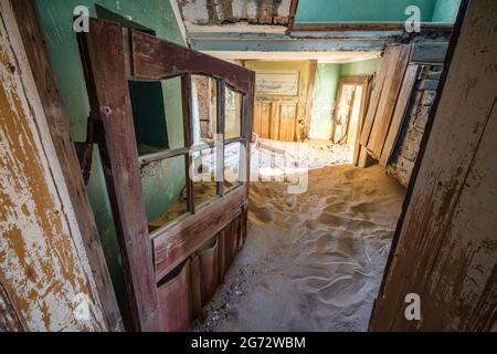L'edificio abbandonato è stato preso in consegna dalla sabbia incrostata nella vecchia città mineraria di Kolmanskop vicino a Luderitz, Namib Desert, Namibia. Foto Stock